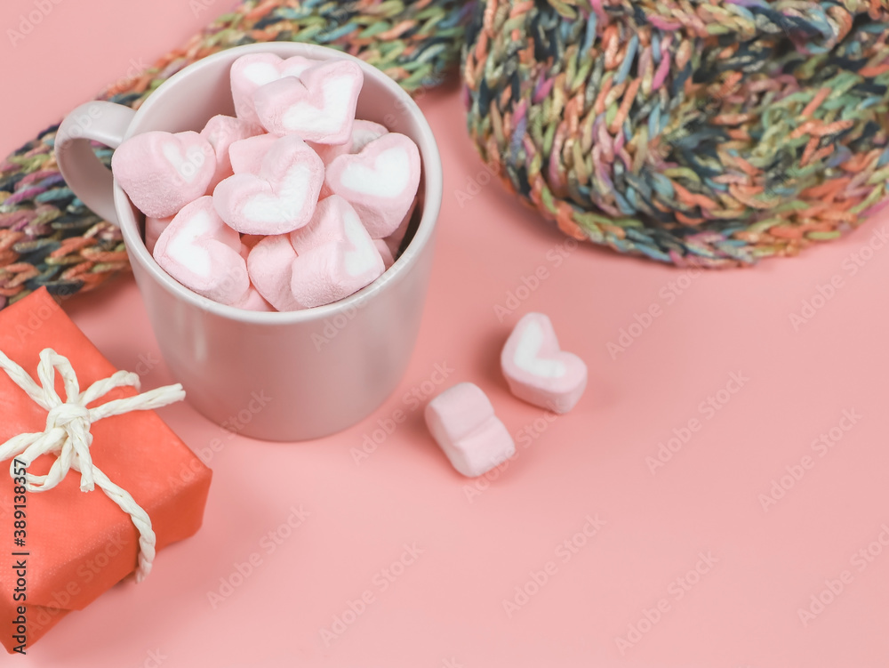 heart shape marshmallows in pink cup  on wth red gift box and  colorful scarf on pink background with copy space.