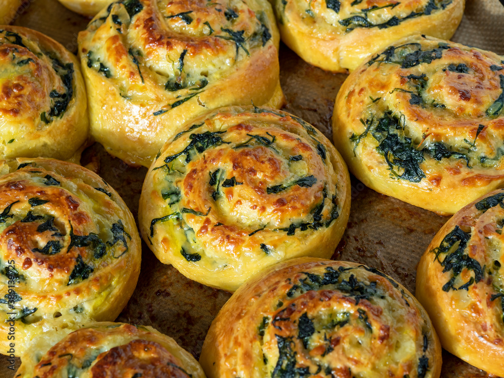 dough curls with spinach and cheese on a baking sheet. Top view