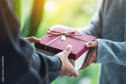 Closeup image of a man giving a woman a gift box photo