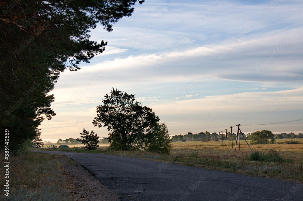 Suburban highway and fog over a field in the early autumn morning. Ryazan region. Russia. Suburban highway and fog over a field in the early autumn morning. Ryazan region. Russia.