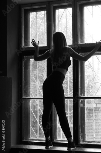 Silhouette against the window, black and white photo of a girl on the windowsill.