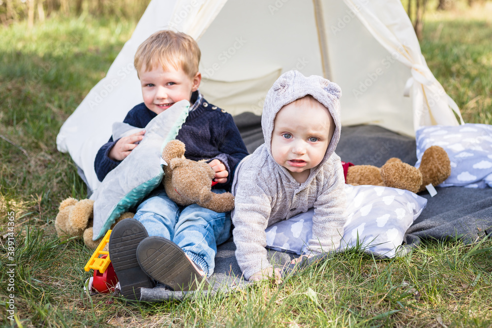 Two little boys - brothers playing in the teepee tent outdoors Two little boys - brothers playing in the teepee tent outdoors