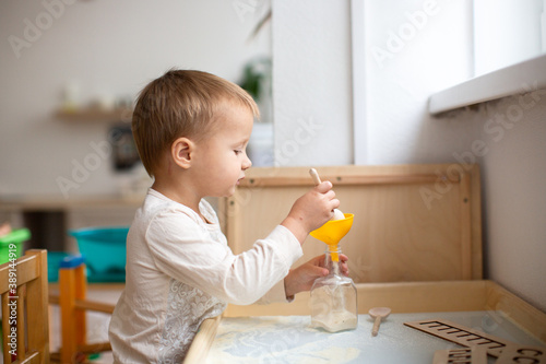 Toddler child plays with free-flowing cereals on the tables. children's center, in a bright house. Fine motor development and sensory development