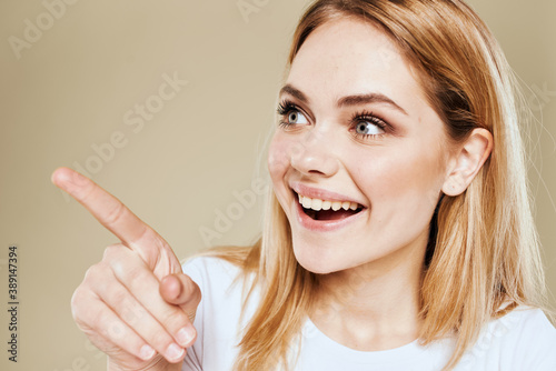 Cheerful blonde gesturing with her hands studio beige background