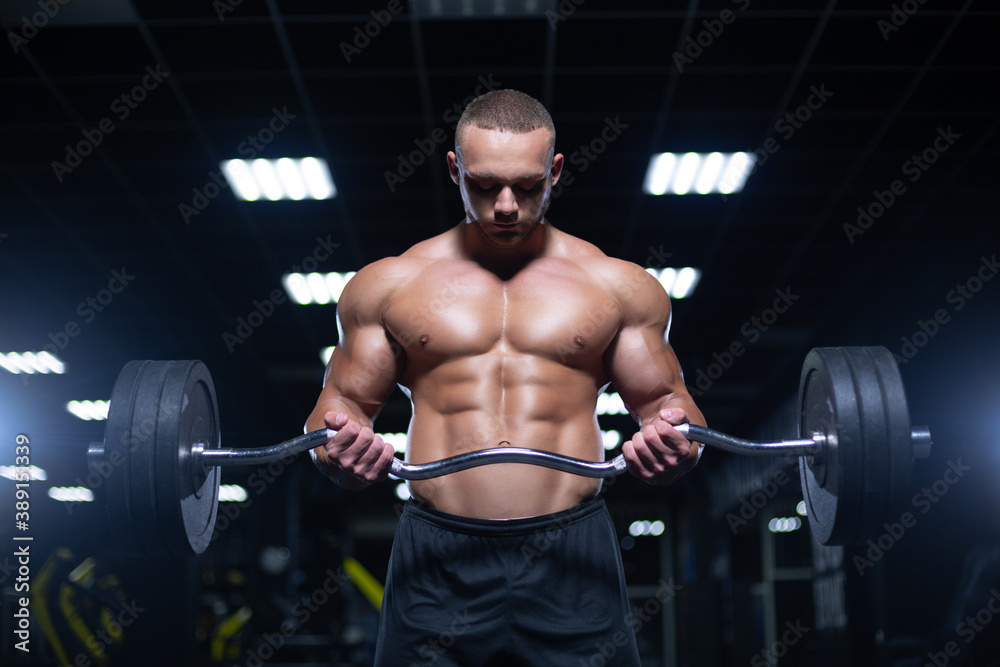 Muscular sexy bodybuilder is working out doing weight lifting of the barbell in gym Muscular sexy bodybuilder is working out doing weight lifting of the barbell in gym