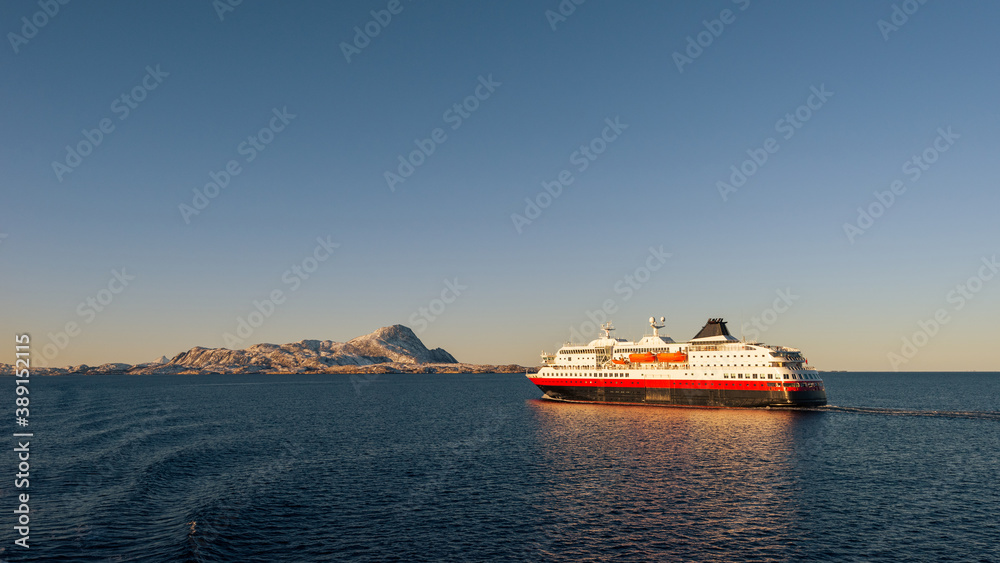 Cruise ship in Norwegian sea in warm bright sunrise morning light on clear winter day