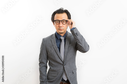 Confident Asian businessman in grey suit and eyeglasses posing standing over white wall background, Business success concept.