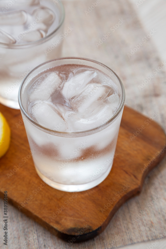 Fresh Lemon Sparkling Water with Ice on a rustic wooden board, side view. Close-up. Fresh Lemon Sparkling Water with Ice on a rustic wooden board, side view. Close-up.