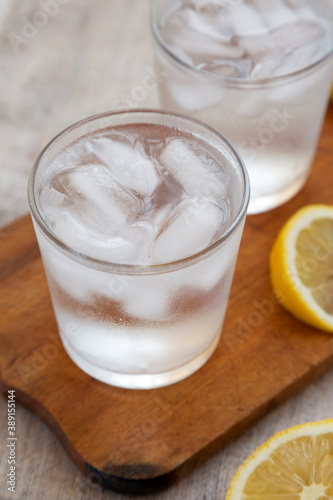 Fresh Lemon Sparkling Water with Ice on a rustic wooden board, low angle view. Close-up.