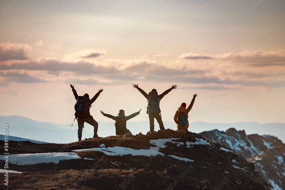 Group of hikers with raised arms at mountain top