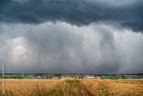 A huge storm cloud with a wall of rain in the countryside.
