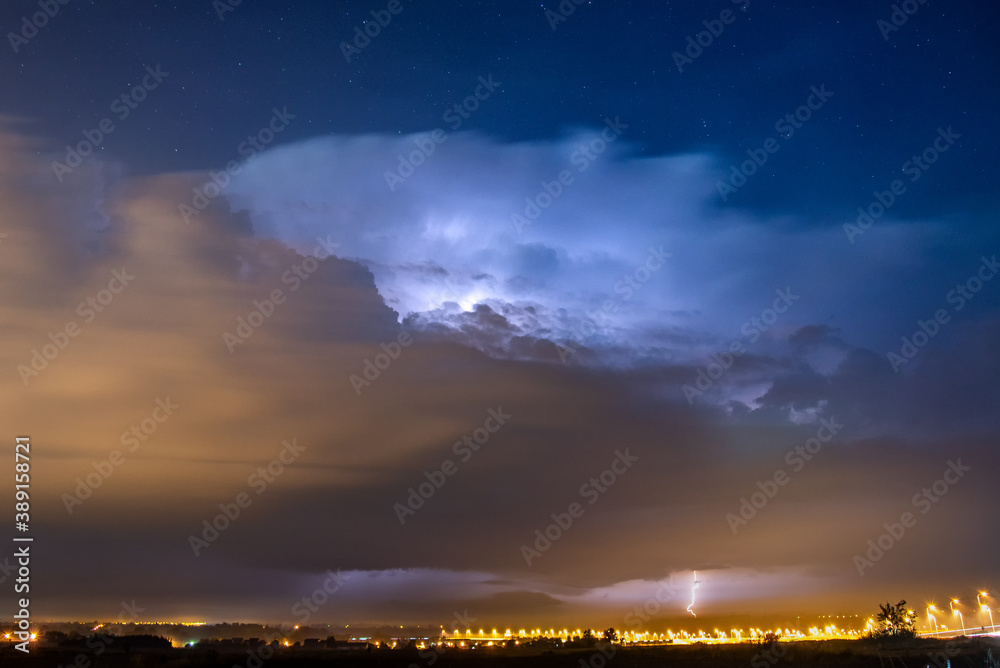 an isolated storm cell with lightning above the city. Cumulonimbus in strong winds and lightning