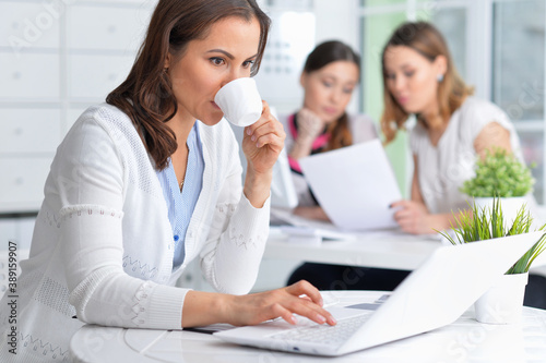 Young women sit at the table and work in a modern office