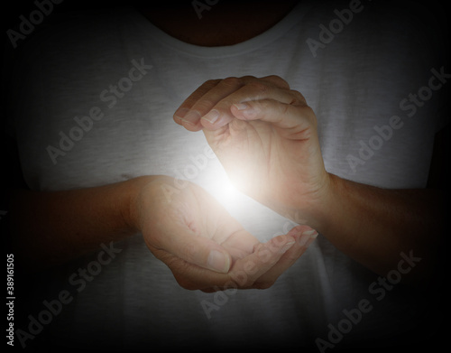 Healer demonstrating how to sense the human electromagnetic with hands - woman in a white top with hands cupped around a white ball of energy 
 photo