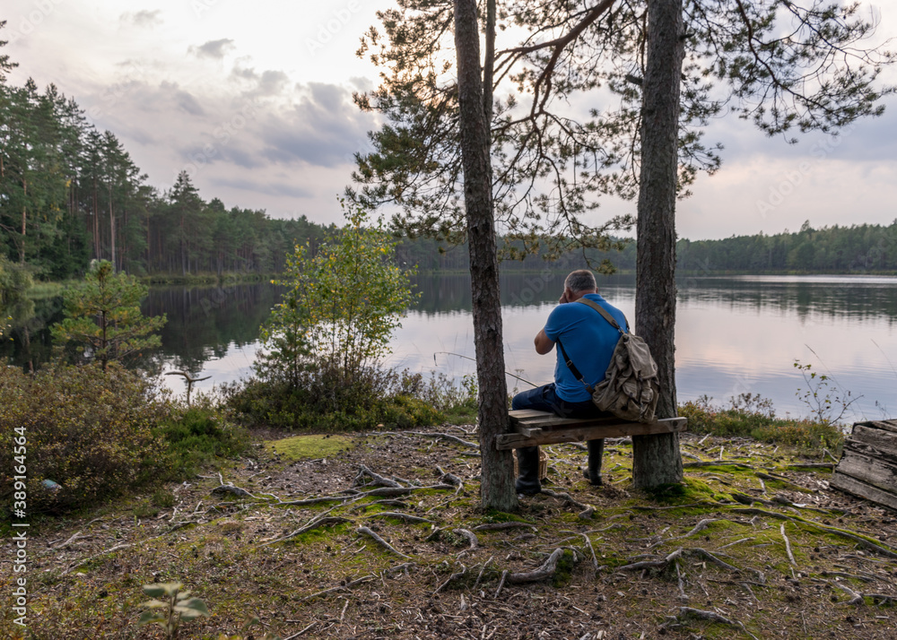 silhouette of a sitting man on a bench by the bog lake, bog lake landscape, autumn