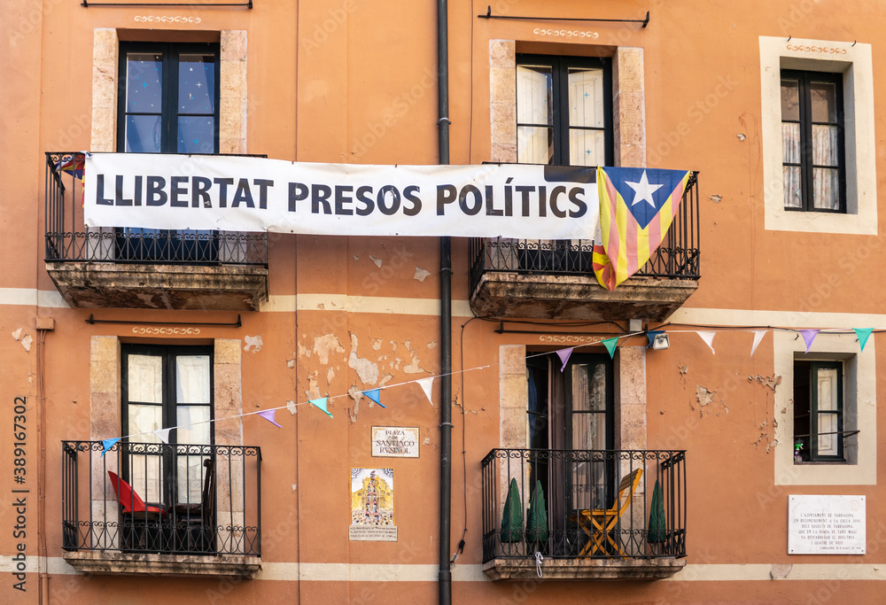 Naklejka premium Spain; Oct 20: Catalan flag and banner with political message on the balconies of a traditional house. Freedom for political prisoners. Catalan symbols castells, estelada. Tarragona, Catalonia, Spain