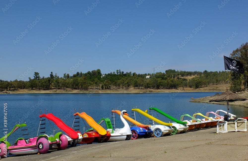 Fototapeta premium Colorful pedal boats on the beach of the Orellana dam, Extremadura - Spain
