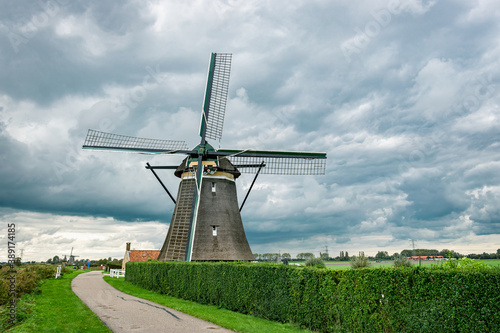 Dutch windmill along river Rotte in western part of The Netherlands. Angry sky as background.