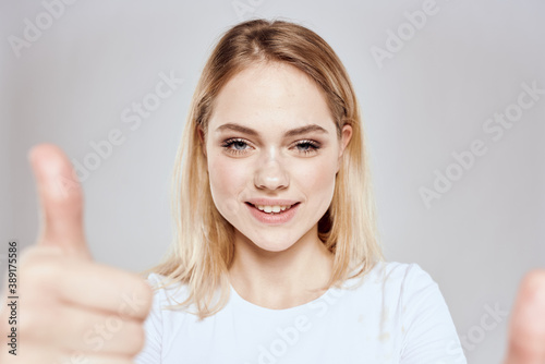Cheerful blonde woman in white t-shirt cropped view light background