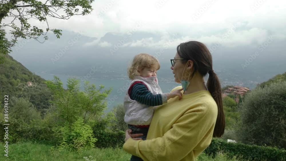 Millennial mother uses face covering to play peekaboo with her adorable, curly, toddler son Millennial mother uses face covering to play peekaboo with her adorable, curly, toddler son