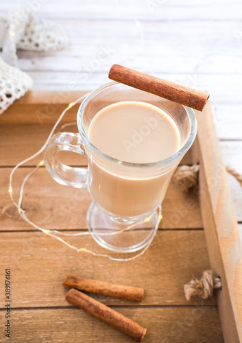 Traditional winter eggnog in glass mug with milk, rum and cinnamon, christmas decorations.