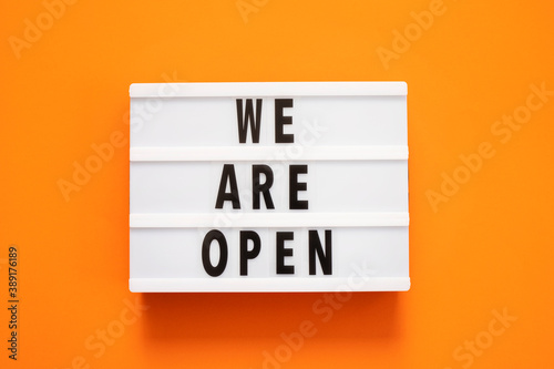Concept of the end of quarantine. Lightbox with text message We are open on a orange background. Hotel, store, cafe, business. Notification of the end of quarantine. photo
