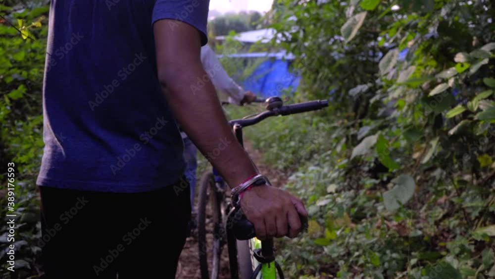 cyclist walking with cycle bike in the deep jungle looking choosing for path in sun rays slow motion 120 hand on a seat close up cyclist walking with cycle bike in the deep jungle looking choosing for path in sun rays slow motion 120 hand on a seat close up