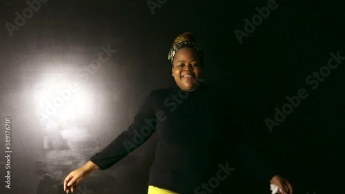 Happy Black woman with braids spins happily while smiling and looking directly in camera photo