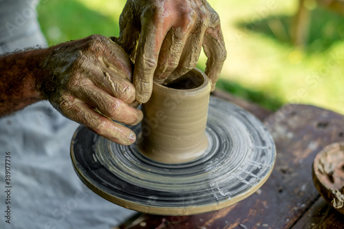 Hands of a potter shaping a clay pot on a potter wheel