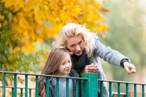 Canvas Print Mother and daughter at park in autumn in London - Happy mom and girl wearing war