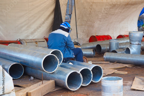 Worker sitting on pipes at construction site.  photo