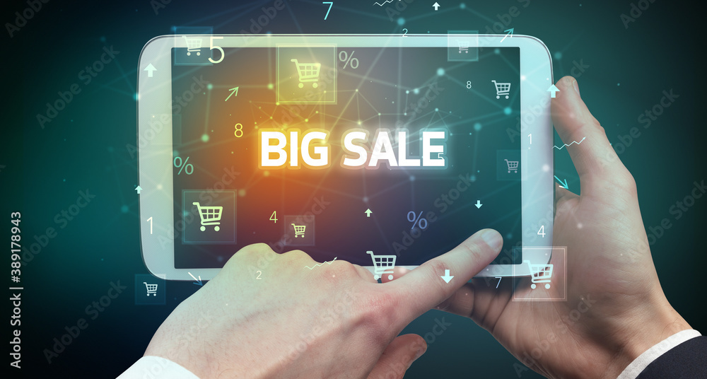 Close-up of a hand holding tablet with BIG SALE inscription, online shopping concept Close-up of a hand holding tablet with BIG SALE inscription, online shopping concept