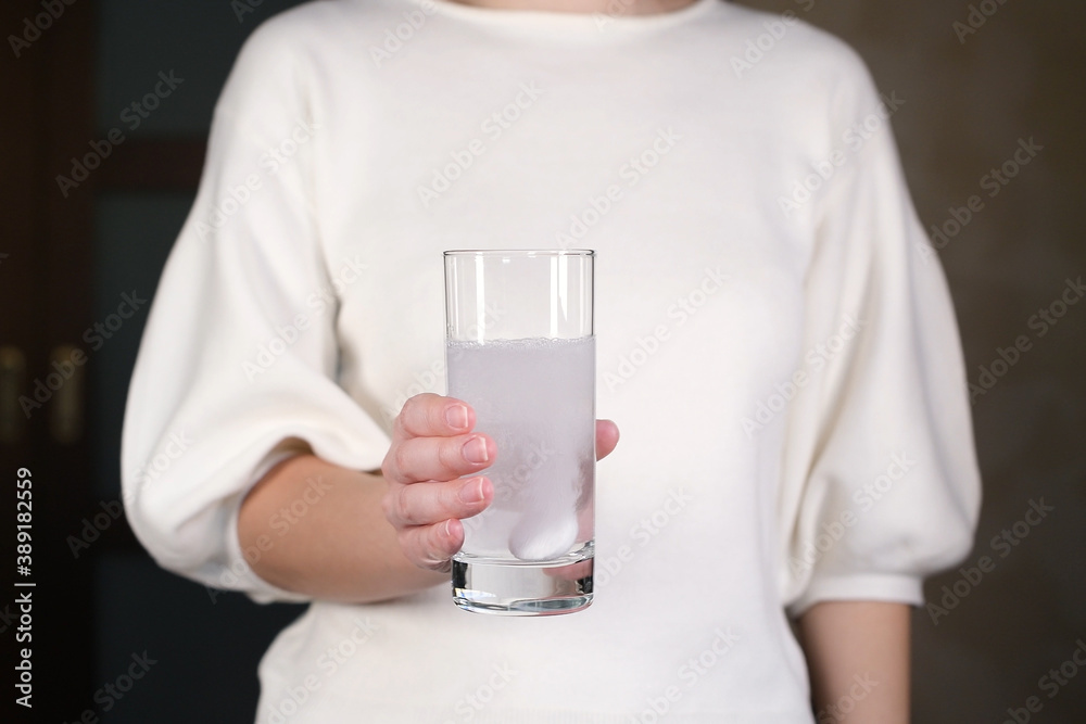 woman holds glass of water with effervescent tablet of aspirin woman holds glass of water with effervescent tablet of aspirin