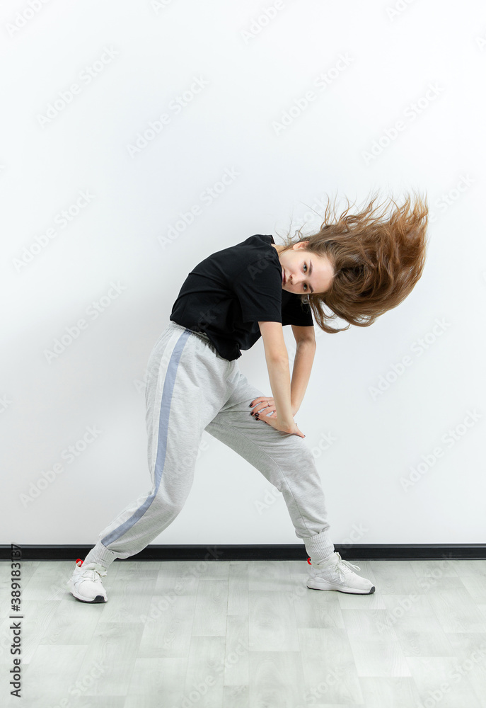 Young beautiful athletic girl dancing hip-hop in the studio
