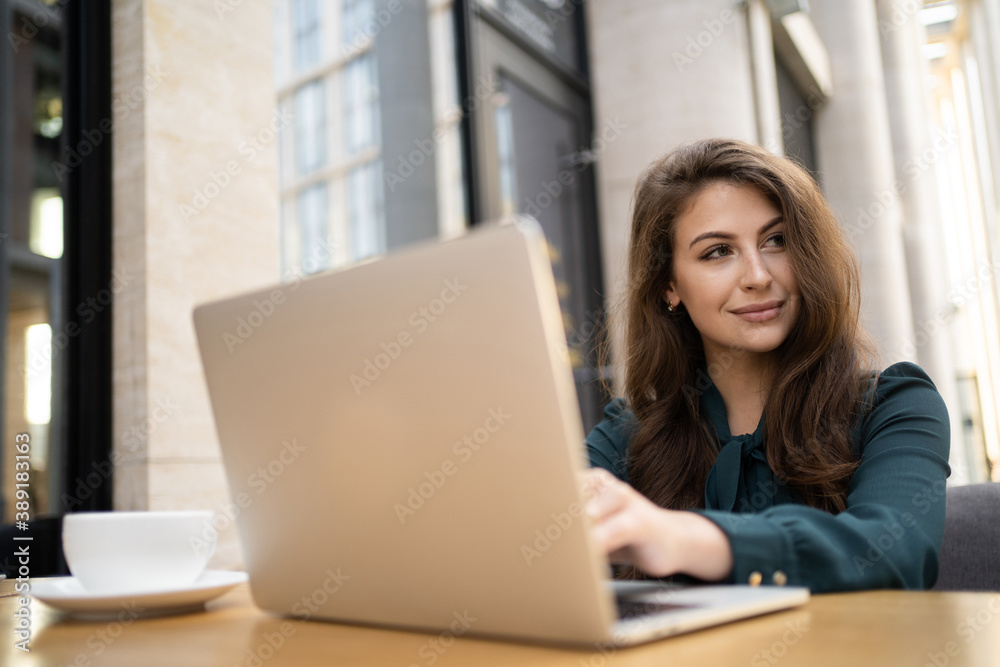A woman manager in a cafe uses a laptop. A woman manager in a cafe uses a laptop.