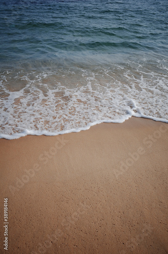 젖은 모래와 잔잔한 파도가 치는 바다의 풍경
