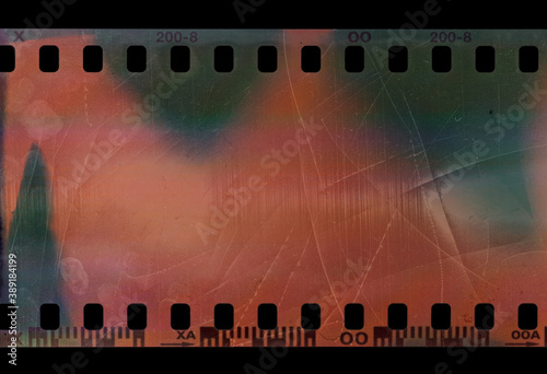 detail shot of short 35mm film snip or strip on black background with scratches and fingerprint texture.
