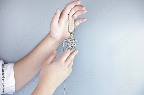 teenager hand holding a gem turtle pendant. young woman's hands with hanging gemstone turtle. beautiful spakling acsessories. holidays concept. crop view