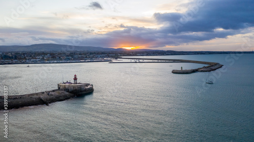 sunset over the harbor, two lighthouses, town landscape, mountains on the horizon