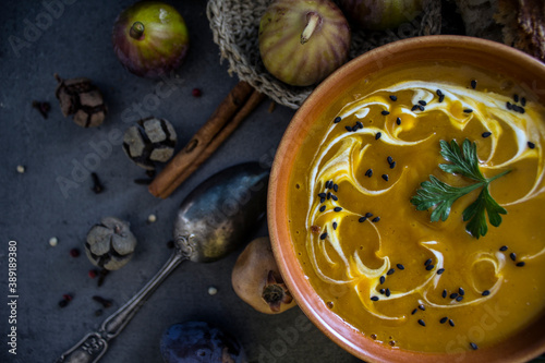 Pumpkin soup decorated with creamy sauce, black sesame seeds and parsley. Close up photo of vegetarian meal. 