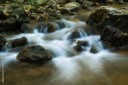 The stream of water in the river flowing between the rocks , long exposure photo