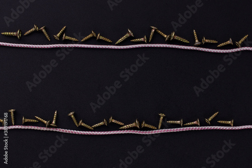 the background for the text is made of self-tapping screws and rope on a black background (top view).