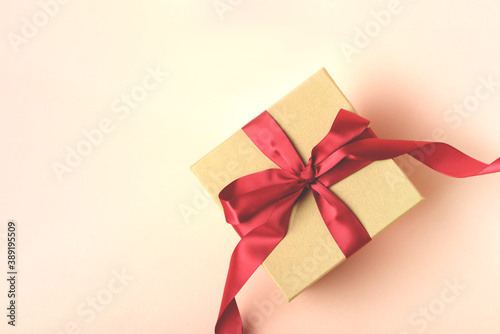 A beautiful craft gift-box with red ribbon on the pink background. Holiday concept. Place for your text.