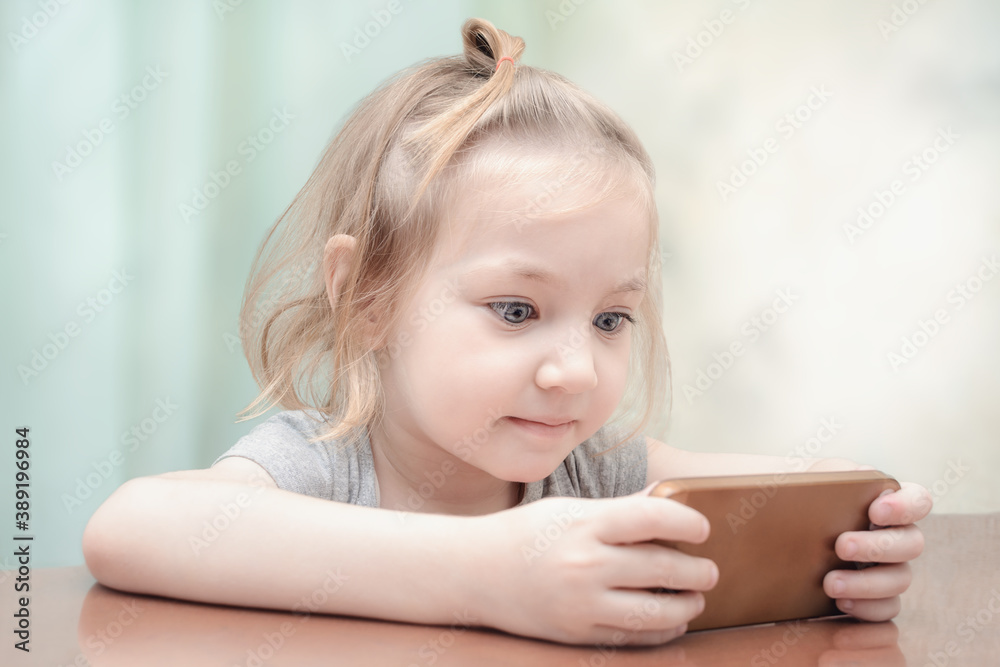 Small child looks at the phone with surprised look. Small child looks at the phone with surprised look.