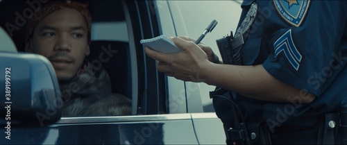 African-American black driver is being pulled off by mixed-race female police officer. Documents check, speeding ticket