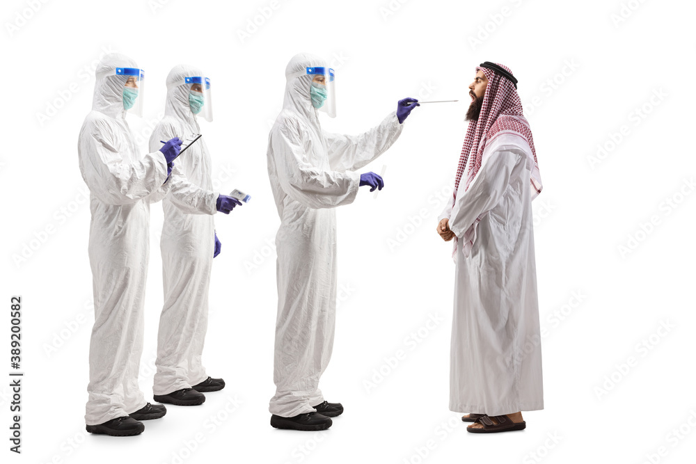 Full length profile shot of medics in hazmat suits testing an arab man for covid-19