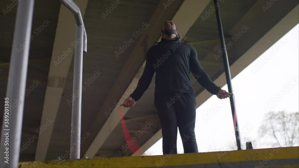 Camera moves from left to right as a man skips with a jump rope, in slow motion Camera moves from left to right as a man skips with a jump rope, in slow motion