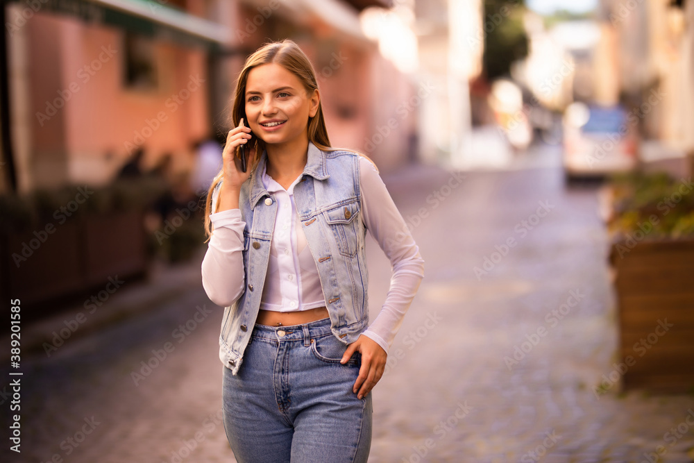 Young woman using mobile cell phone over city background.