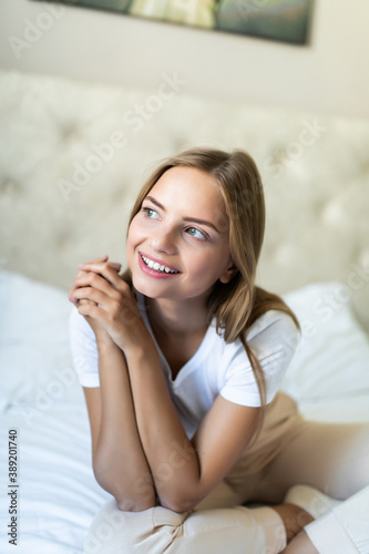 Young beautiful woman sitting on bed at home