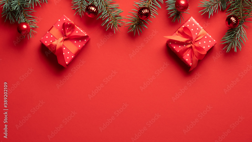 Christmas gift boxes and fir tree branches decorated balls on red background. Xmas holiday background, frame border, banner mockup.